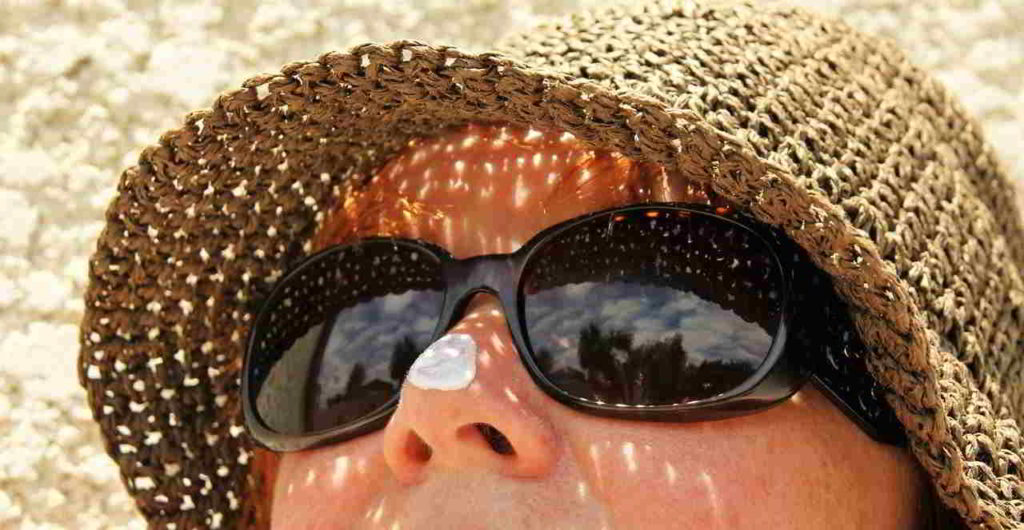 Mujer protegiéndose del sol con gorro y gafas