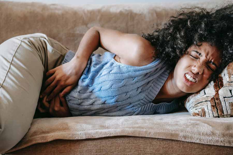 Chica tumbada en el sofá con dolor de estómago o gastralgia